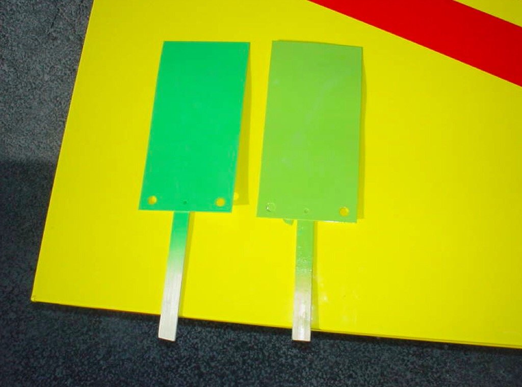 Duas plaquetas de amostra de cor PTS verdes apoiadas sobre uma peça pintada de amarelo