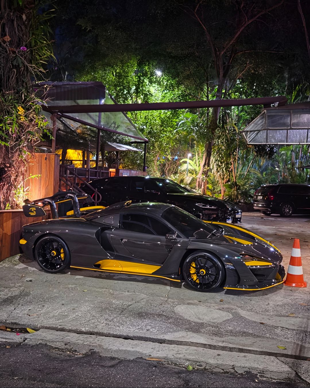 McLaren Senna de carbono escuro com detalhes amarelos, à noite em São Paulo