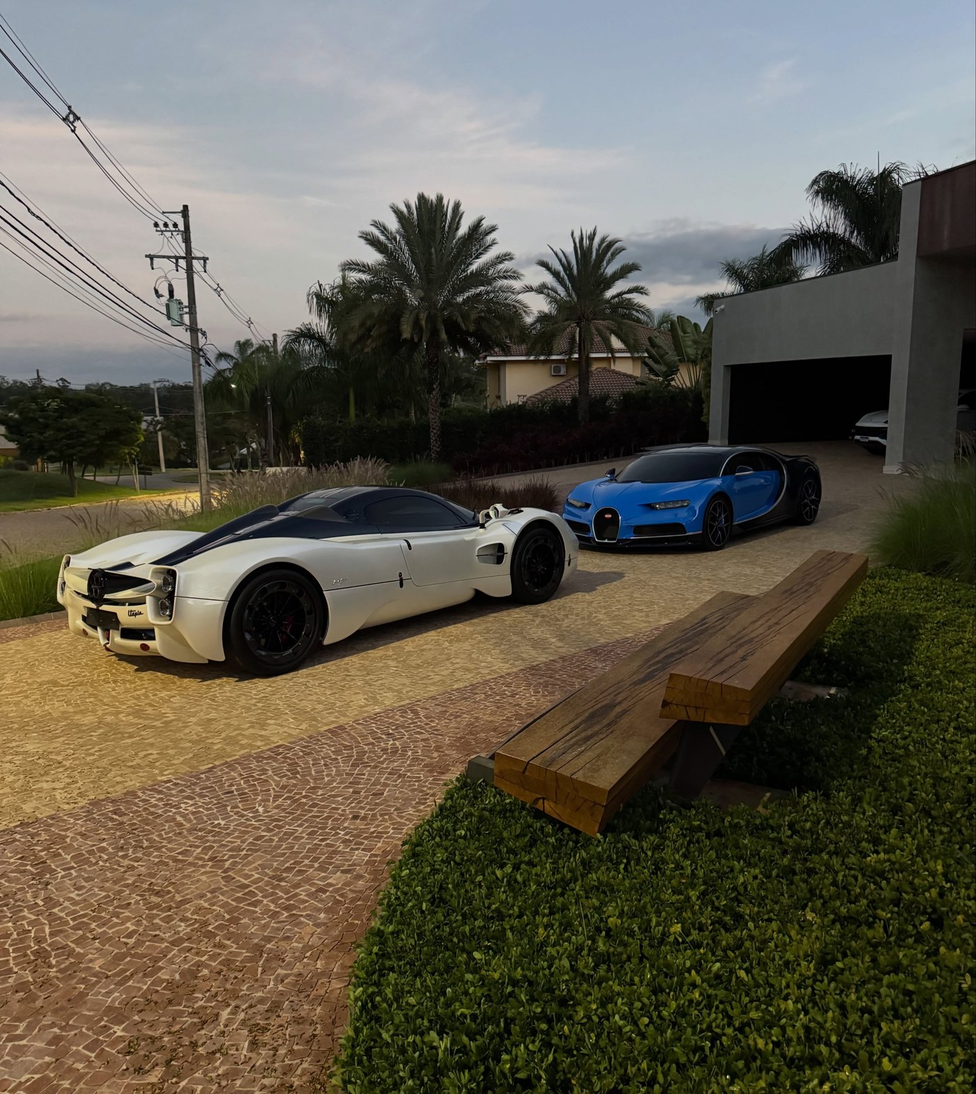 Pagani Utopia branco e Bugatti Chiron azul estacionados lado a lado em Itu, com palmeiras ao fundo